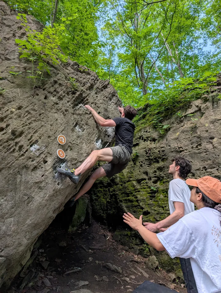 Bouldering on an overhanging rock face in the woods